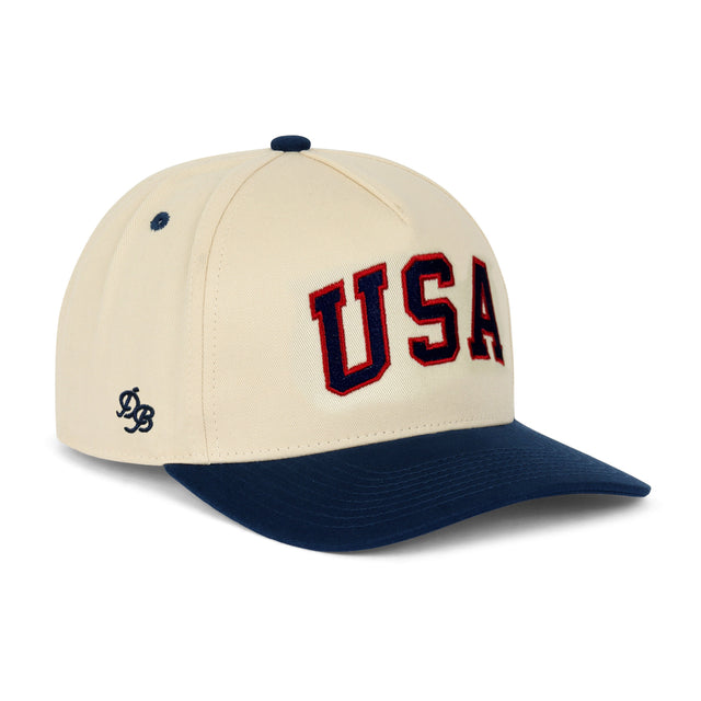 USA Structured Snapback Hat – Embroidered cream and navy 5-panel snapback with USA lettering. A classic patriotic hat and gift from Dad Brand.